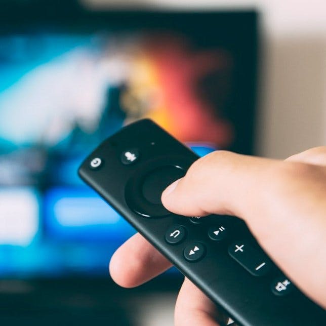hand of a person with a remote control pointing on the tv